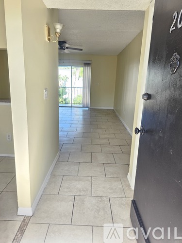 A hallway with a black door and tiled floor.
