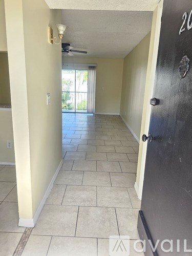 A hallway with a black door and tiled floor.