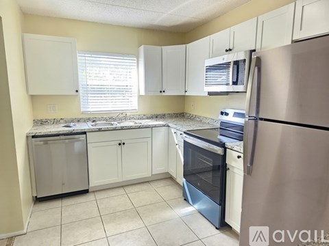 A kitchen with a stainless steel refrigerator, white cabinets, and a granite countertop.