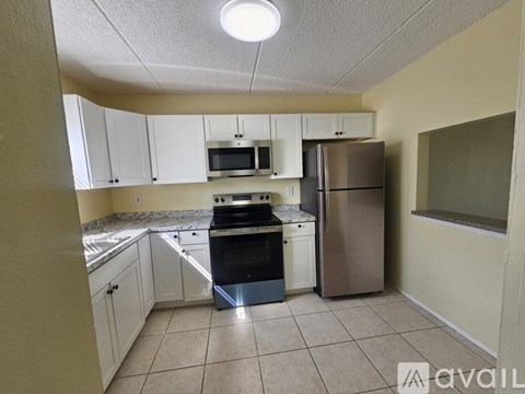 A kitchen with white cabinets and a stainless steel refrigerator.