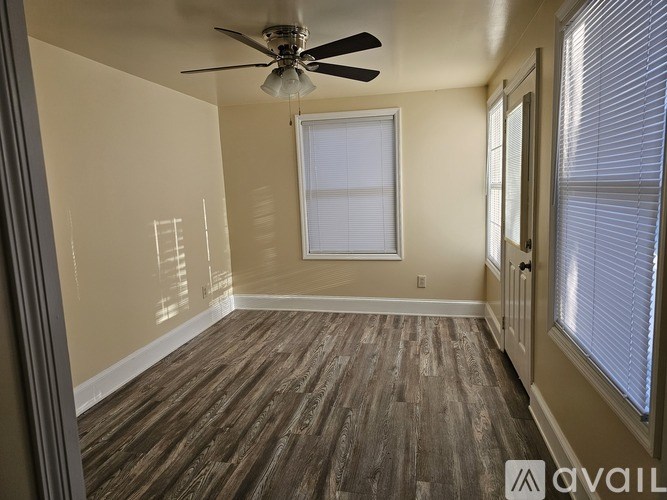 A room with a ceiling fan and wooden flooring.