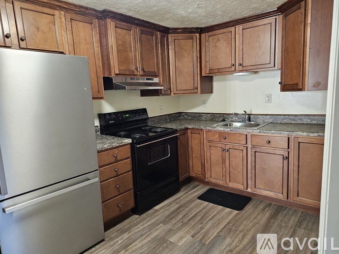 A kitchen with wooden cabinets and a stainless steel refrigerator.