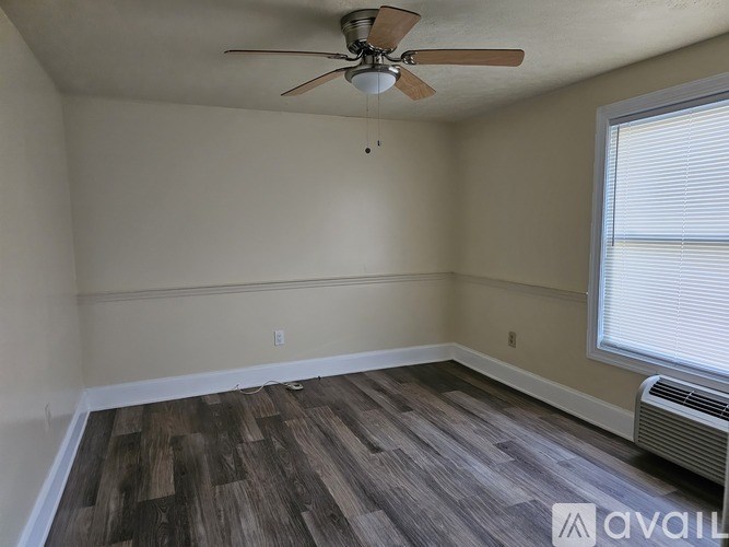 A room with a ceiling fan and wood flooring.