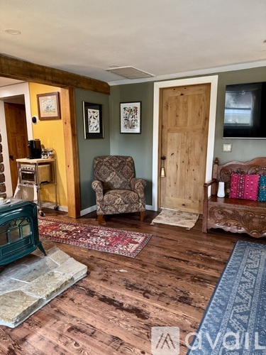 A living room with a brown wooden floor and a blue rug.