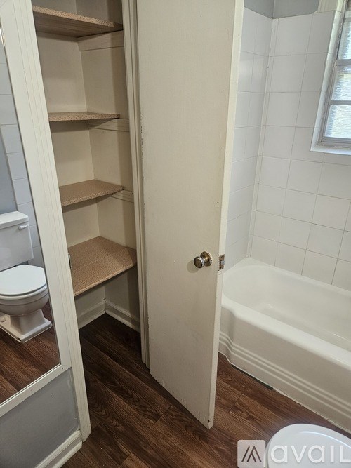 A white door is open to a small bathroom with a toilet and a bathtub.