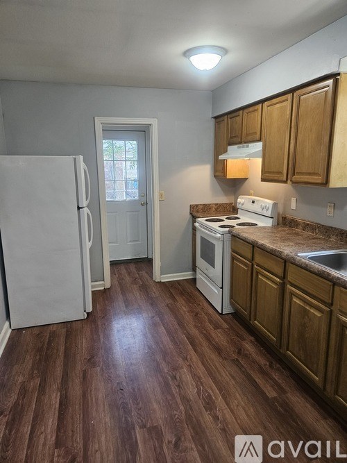 A kitchen with a white fridge, stove, and wooden cabinets.
