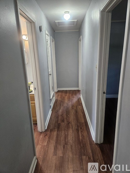 A long hallway with wood floors and white walls.