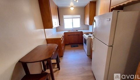 A kitchen with a table and chairs in front of a refrigerator.