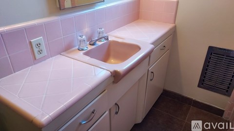 A bathroom with a pink tile backsplash and a white sink and toilet.