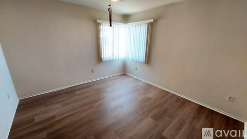 A room with wooden flooring and a window with blinds.
