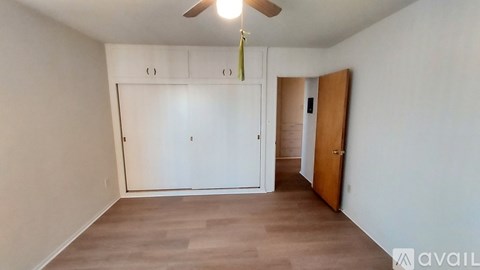 A room with a ceiling fan and a door on the right.