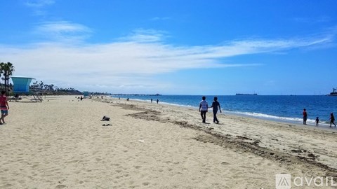 A beach scene with people walking and playing on the sand.