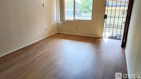 A room with wooden flooring and a sliding glass door leading to a balcony.