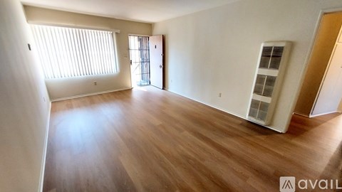 A spacious room with wooden flooring and a large window.
