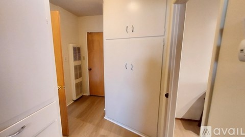 A white refrigerator in a kitchen with a wooden door.