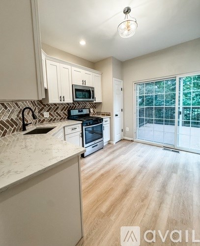 A kitchen with a white countertop and wooden flooring.