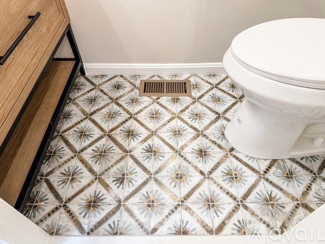 A white toilet sits in a bathroom with a patterned floor.