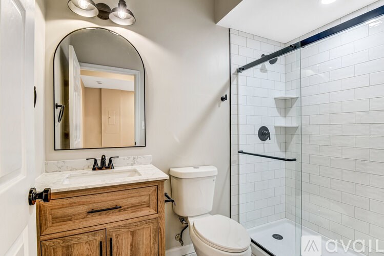 A white bathroom with a wooden cabinet and a black and white floor.