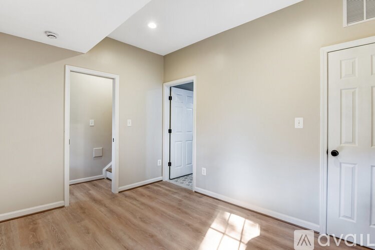 A wooden cabinet with a marble top is in front of a toilet paper roll and a round mirror.