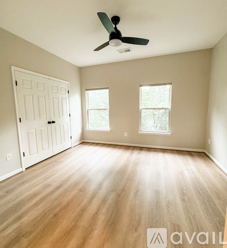 A room with a ceiling fan and two windows.