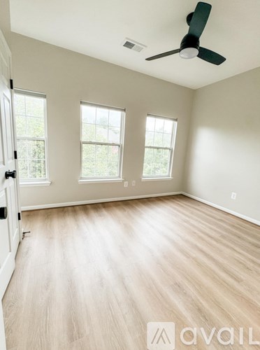 A room with a ceiling fan and three windows.