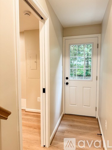 A white door with a black handle is in a room with a wooden floor.