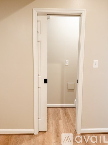 A white door is open to a room with a wooden floor.