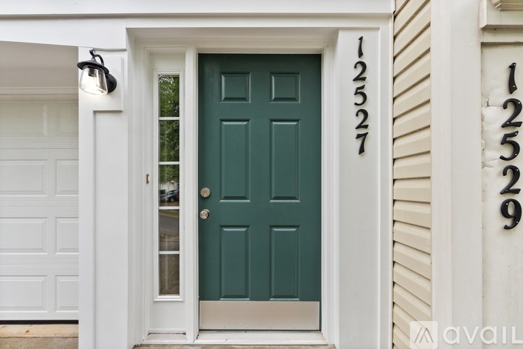 A green door with the number 12527 on the white house.