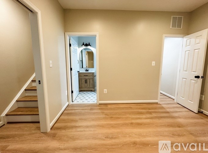 A room with a staircase on the left and a bathroom visible through the doorway.