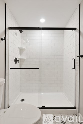 A white bathroom with a toilet and a walk in shower.
