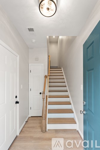 A hallway with a staircase and a blue door.