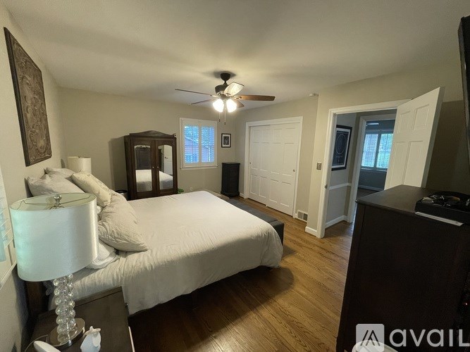 A bedroom with a large bed, a dresser, and a ceiling fan.