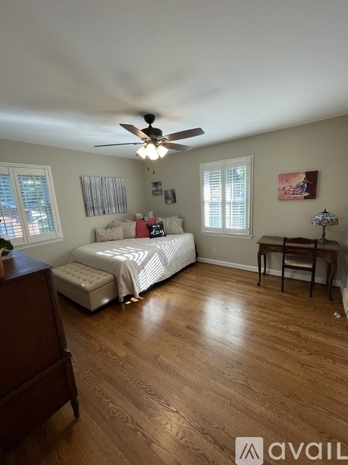 A bedroom with a bed, dresser, and ceiling fan.