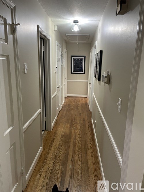 A long hallway with wood floors and white walls.