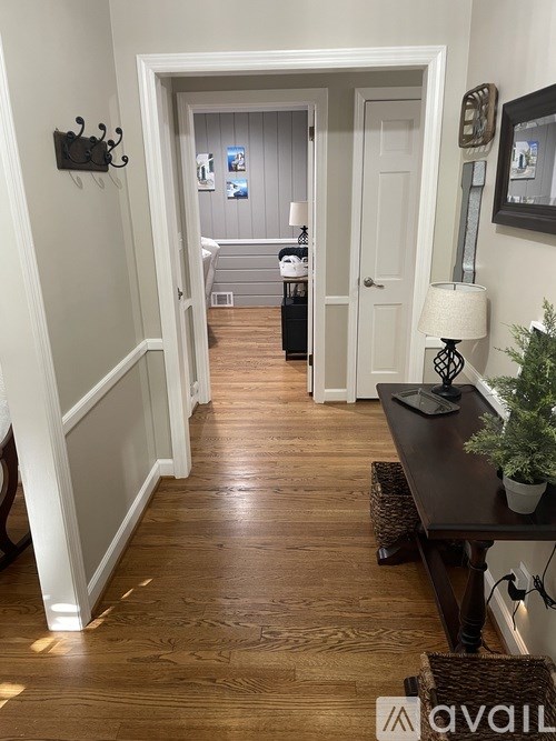 A hallway with a wooden floor and white walls.