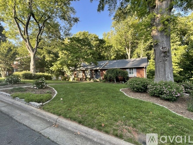 A house with a well-maintained lawn and trees in the background.