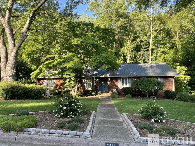 A house with a brick facade and a green lawn in front.