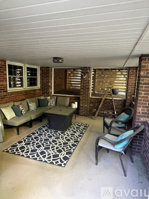 A patio with a couch, chair, and rug.