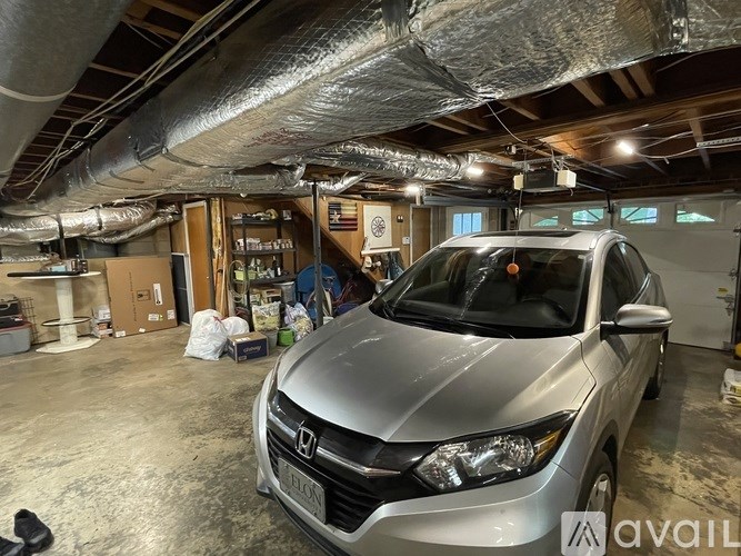 A silver Honda Civic is parked in a garage with a sign that says "AVAIL".