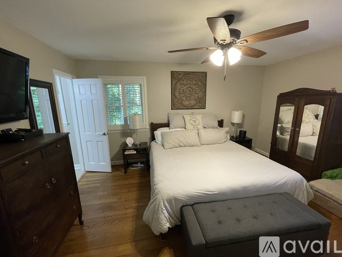 A bedroom with a large bed, a dresser, and a ceiling fan.