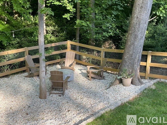 A wooden fence encloses a small garden with a table and chairs.