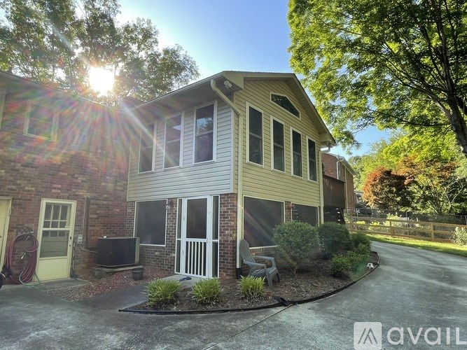 A house with a sunny backdrop and a driveway in front.