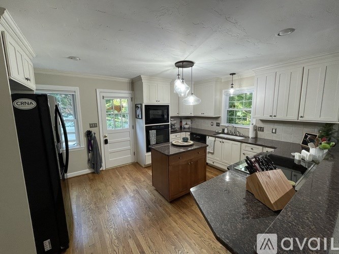 A kitchen with white cabinets and a black refrigerator.