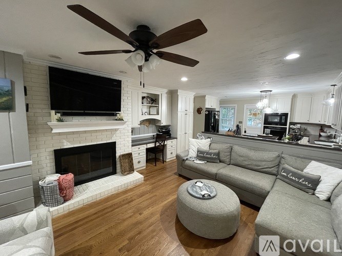 A living room with a fireplace and a television mounted above it.