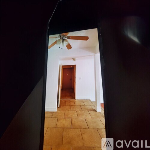 A hallway with a ceiling fan and a door at the end.
