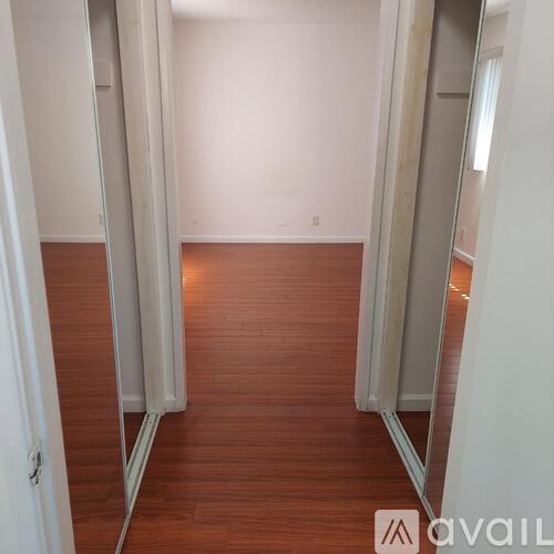 A hallway with a wooden floor and white walls.