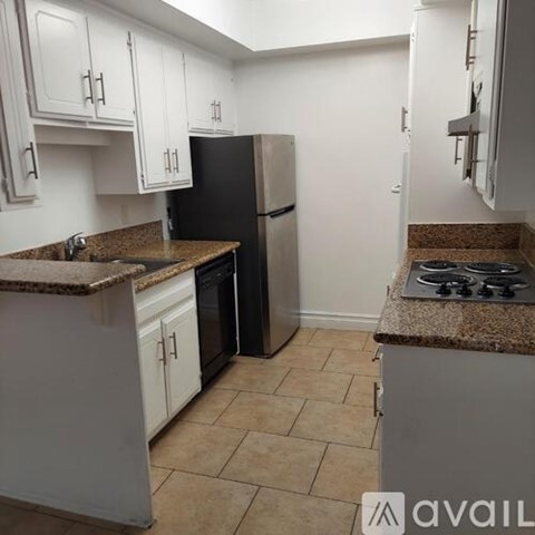 A kitchen with a black refrigerator and white cabinets.