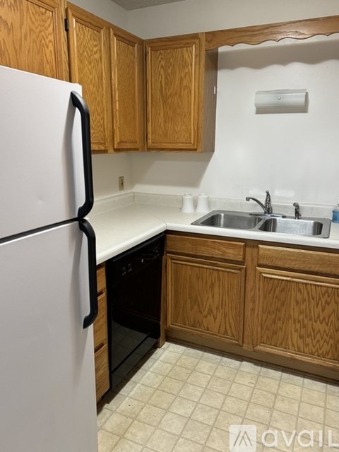 A kitchen with a white refrigerator and wooden cabinets.