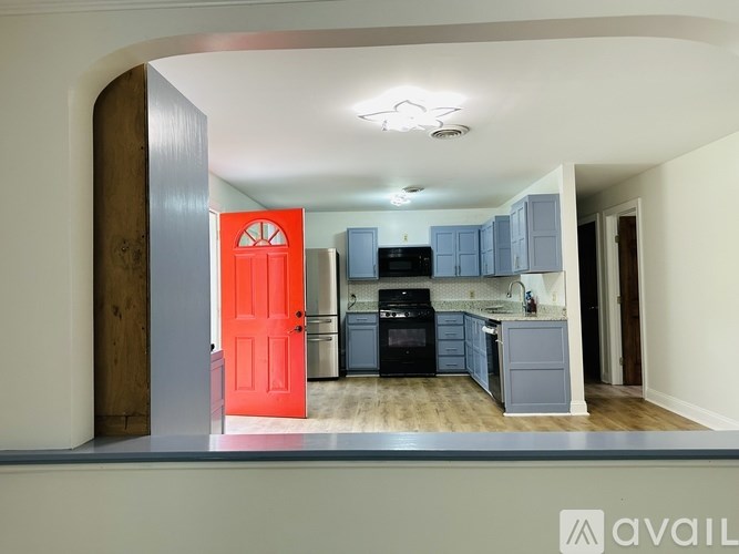 A kitchen with a red door and blue cabinets.