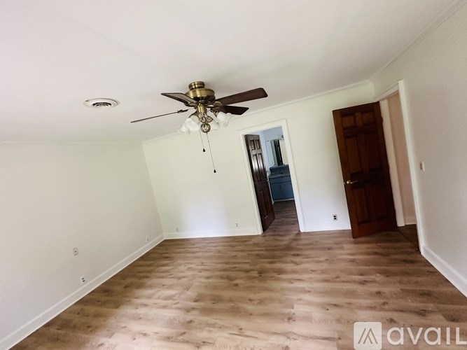 A room with a ceiling fan and wooden flooring.